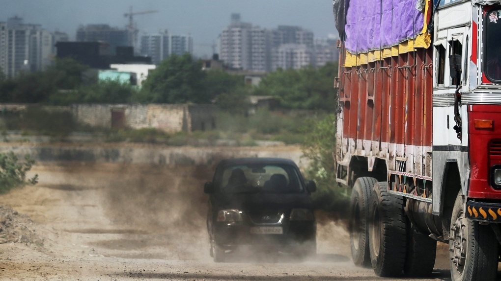 Pollution: An old truck releases excess smoke in front of a car.